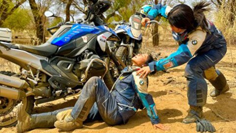 Two riders on the Japanese women’s team, with one of them sitting on the ground, looking exhausted.